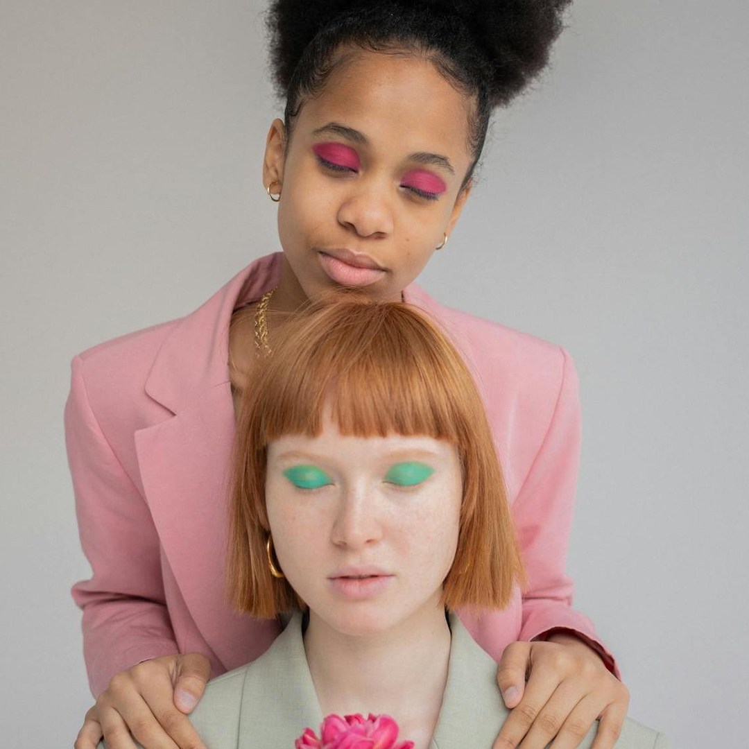 One dark skinned woman, and one fair skin woman both wearing homemade makeup 